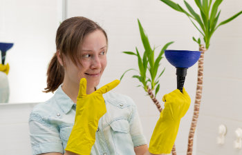 Woman in the bathroom holding toilet plunger