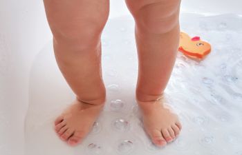 Toddler standing on non-slip mat in the bathtub.