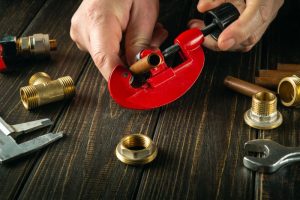 Plumber cutting a copper pipe and fitting it for a new gas line installation.