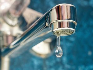 A drop of water dripping from a leaky faucet.