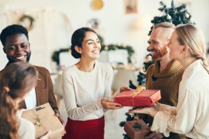 Happy people exchanging gifts during Christmas party at home.