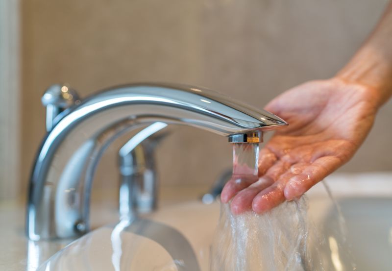 A person in the bathroom checking temperature of running water.
