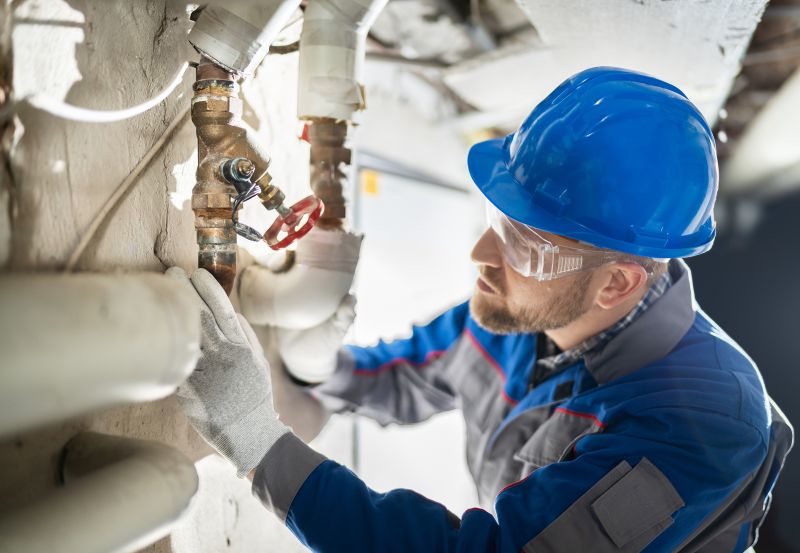 Male Worker Inspecting Water Valve For Leaks In Basement